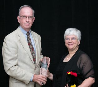 Larry Brown (izquierda), el vice presidente de educación jubilado de USPOULTRY, entregando el prestigioso Premio Carrera Distinguida en la Industria Avícola a la Dra. Janet Fulton, genetista molecular de Hy-Line International.